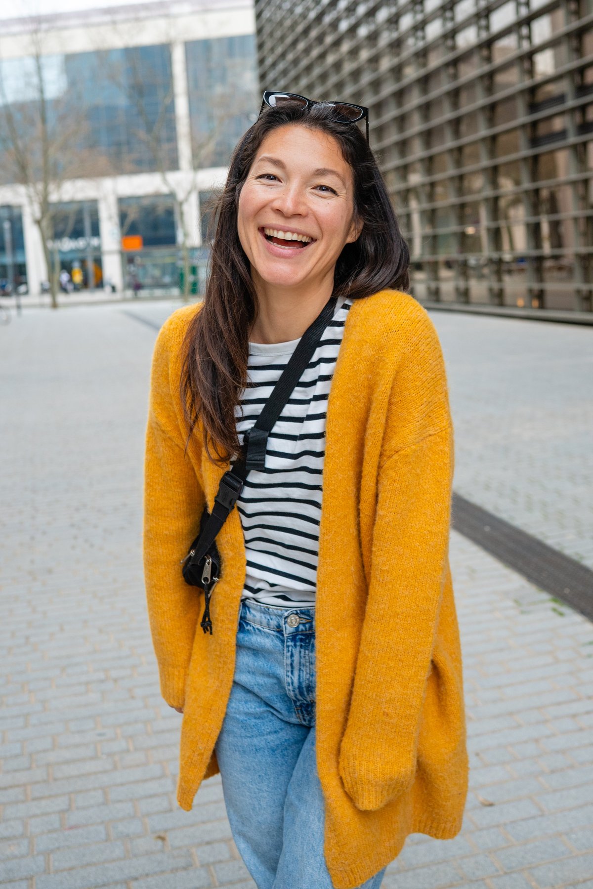 Happy young adult woman laughing cheerfully while standing on a city street