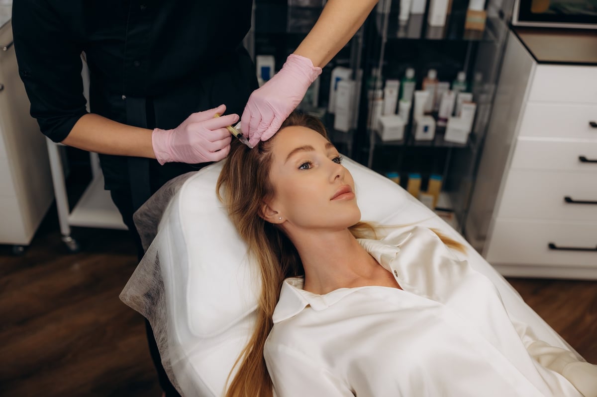Female client undergoing mesotherapy injections in scalp, stimulating hair follicles and fighting alopecia in a beauty clinic